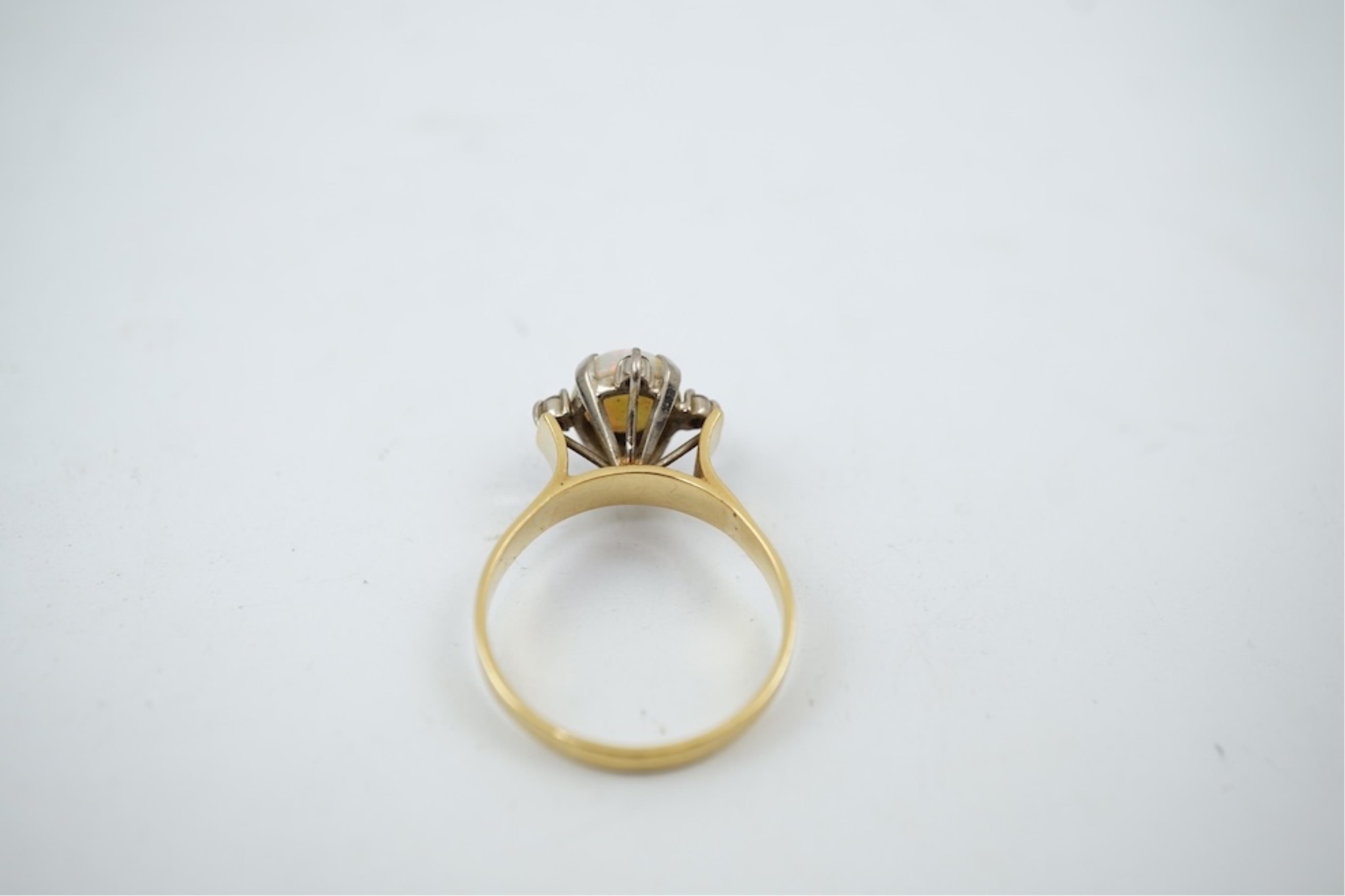 A yellow metal (stamped 18), single stone white opal and four stone diamond chip set ring, size P/Q, gross weight 3.8 grams.